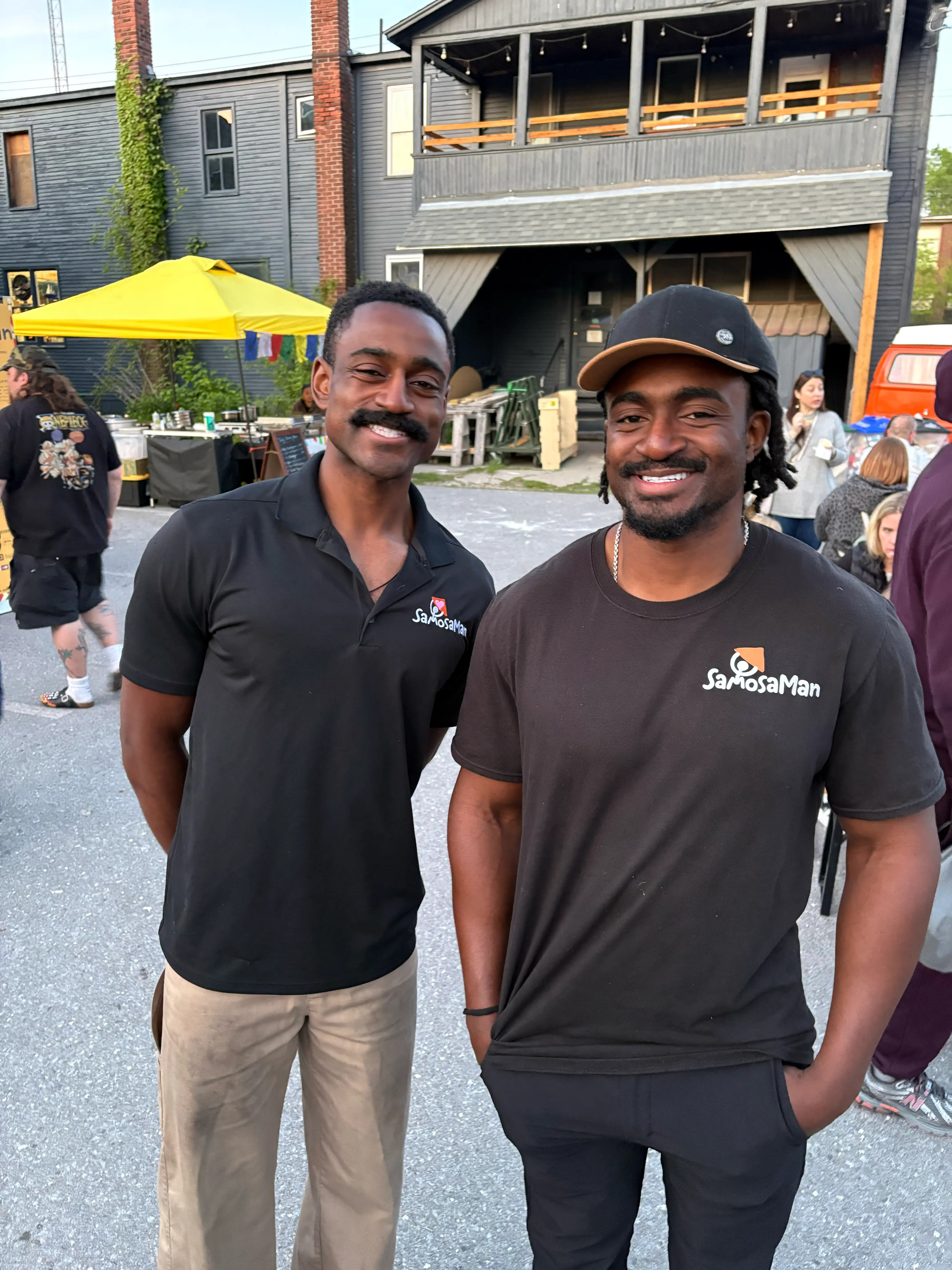 SamosaMan's founders standing behind a tray of freshly folded raw samosas in their Vermont commercial kitchen