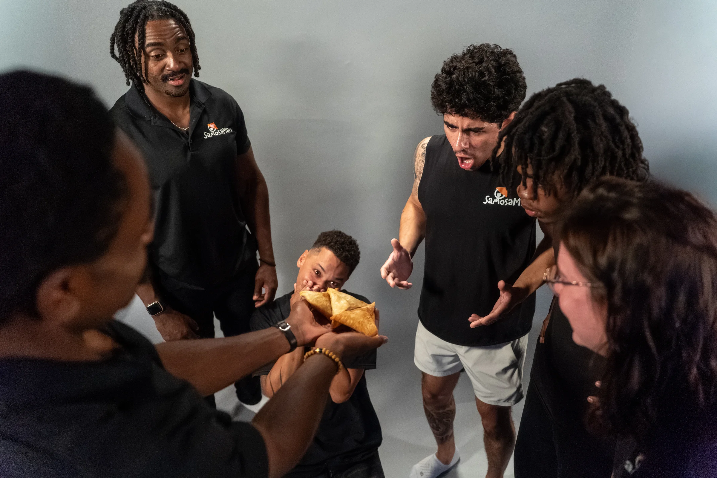 The SamosaMan crew crowding around a handful of golden samosas